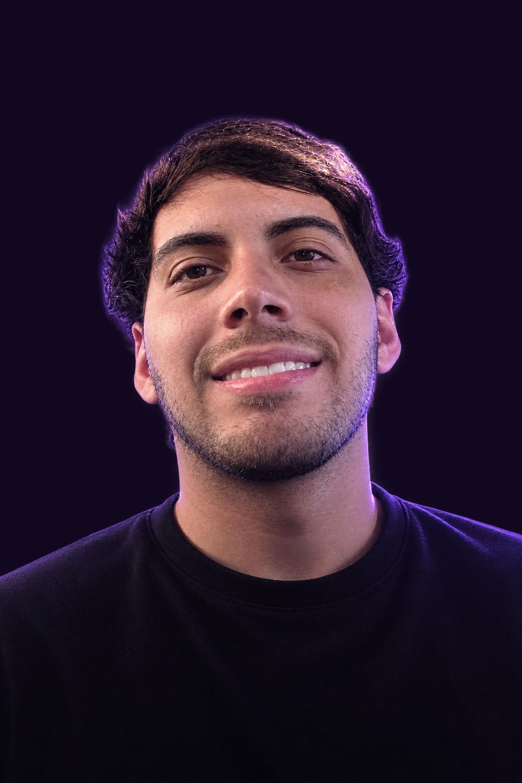 Gianfranco Niveiro sonriendo, con remera negra y luz violeta detrás